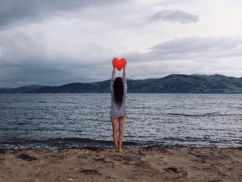 A woman on the beach with a heart signifying that she found love while online dating.