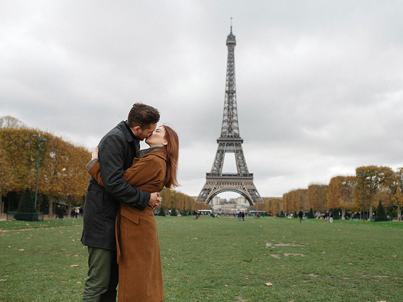 A couple in a healthy relationship kissing in front of the Eiffel Tower.