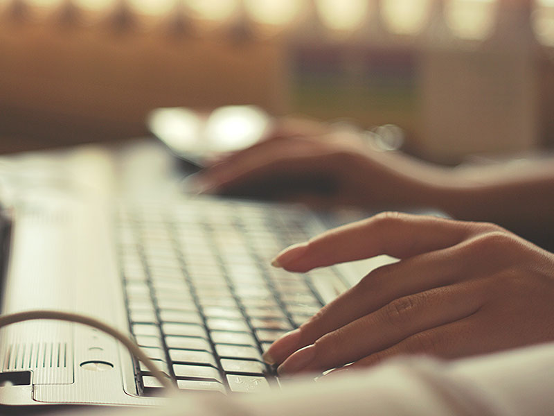 A woman online dating at a computer and typing and online dating message.