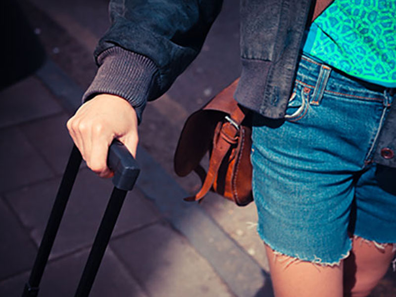 A woman who had relationship problems wheeling a suitcase because she's moving out after a break up.