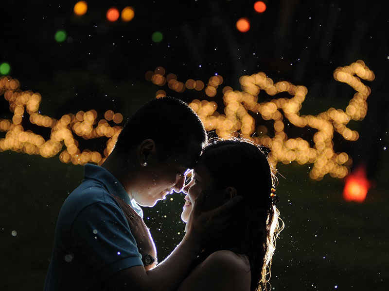 A man and woman at a holiday party looking into each other's eyes.