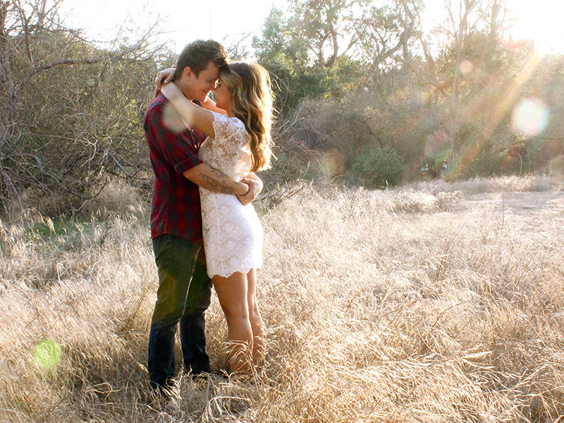 A couple hugging in a field.