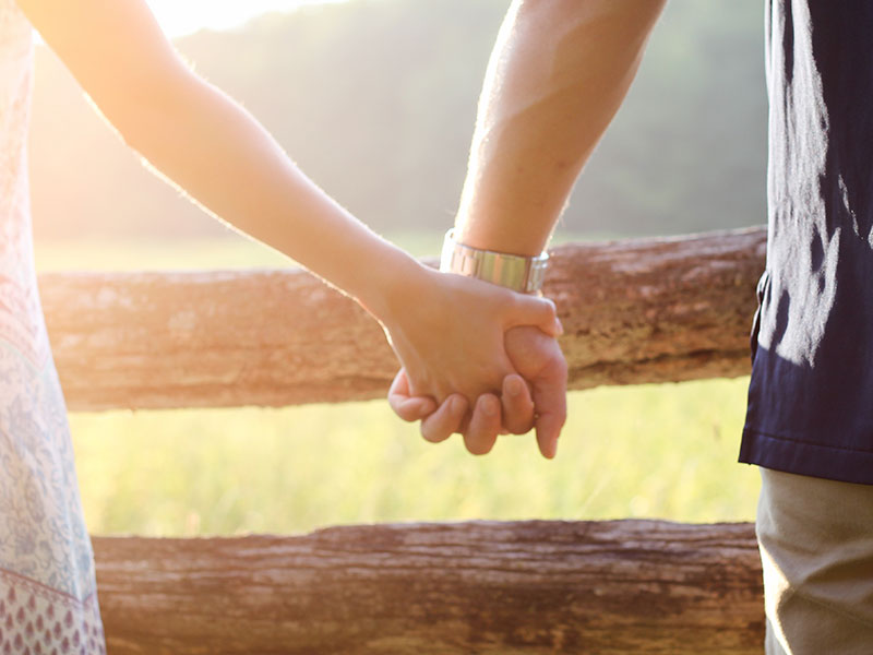 A woman dating a left-handed man holding his hand.