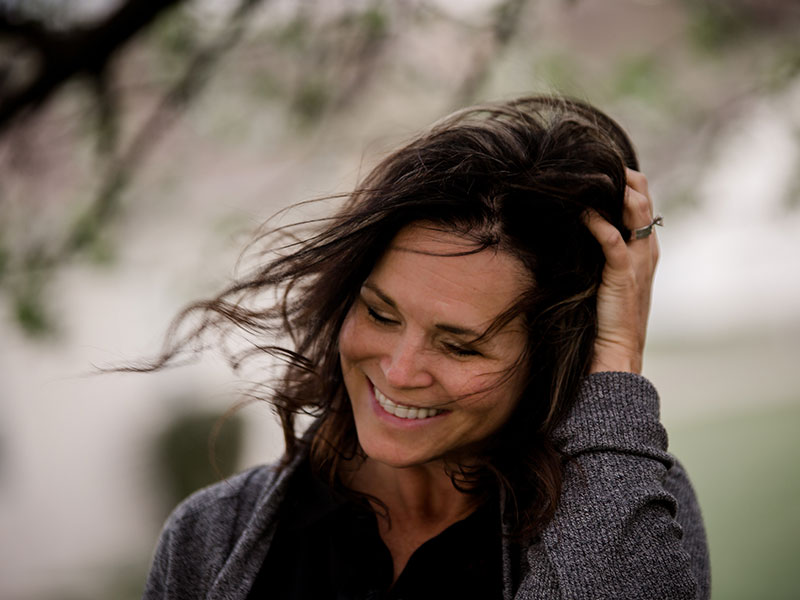 A woman dating over 40 laughing to herself and playing with her hair.