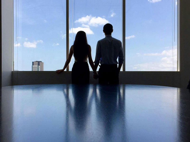 A couple having an office romance holding hands in a conference room.