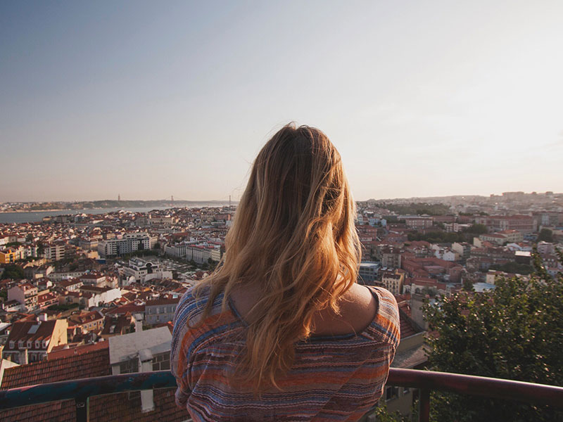 A woman who is wondering how to meet people in a new city looking out over the city wondering.