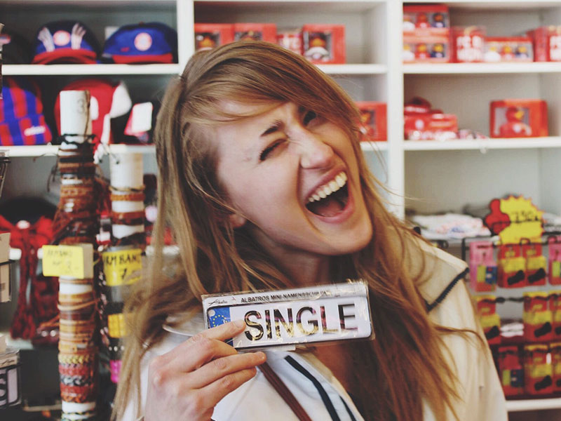 A girl who's single on Valentine's Day smiling and winking.