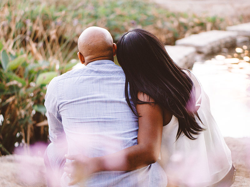 A couple sitting close watching the sunset and displaying one of the traits for a strong relationship--intimacy.