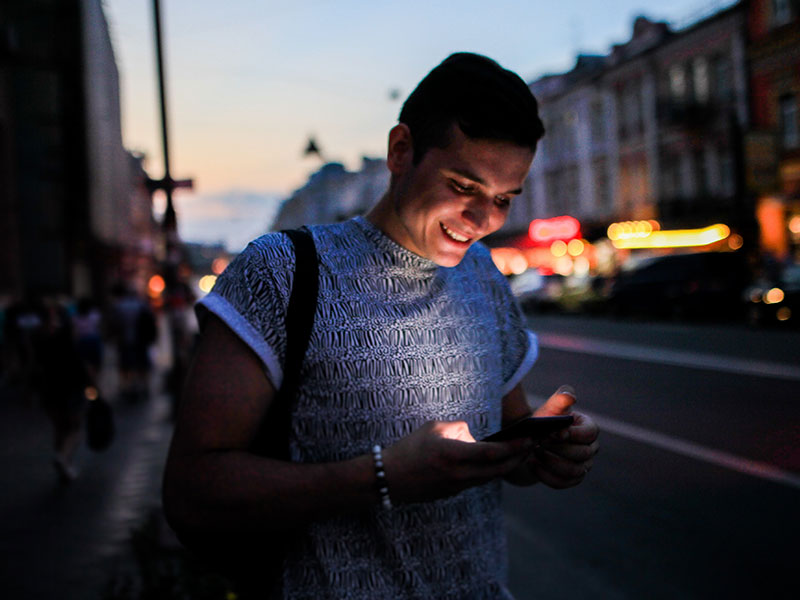 A woman who learned how to spot an online dating scammer laughing while texting someone on a dating app.