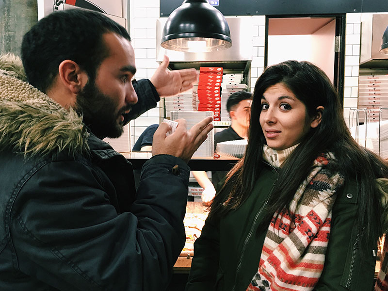 A woman making a face at the relationship red flag of a guy arguing with her over pizza.