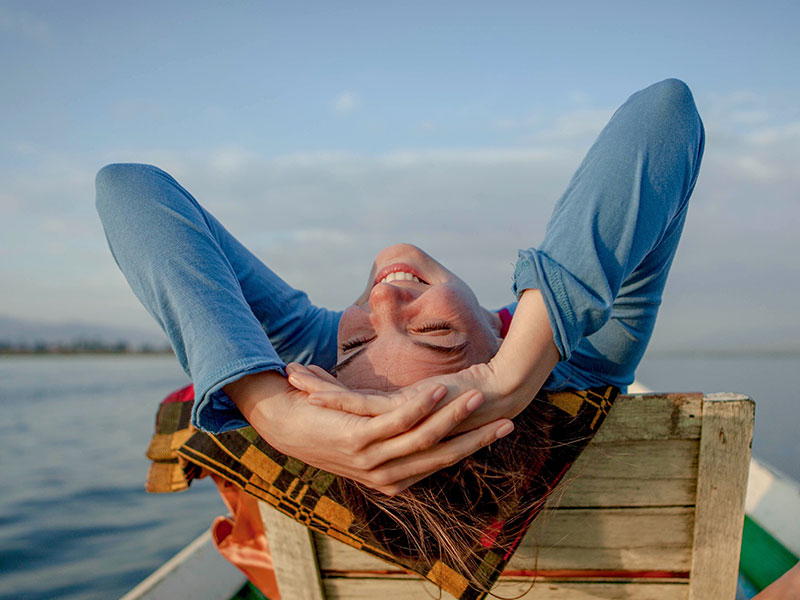 A woman who found it's better to stay single laughing in a beach chair.