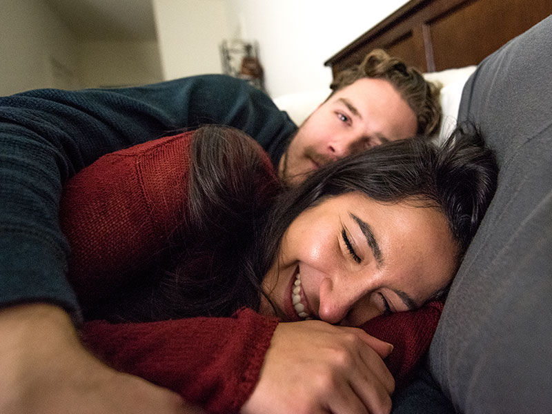 A happy couple who just finishing moving in together giggling in bed.