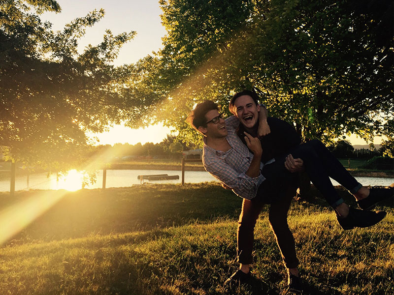 Two guys who listened to these dating tips laughing in a field together.