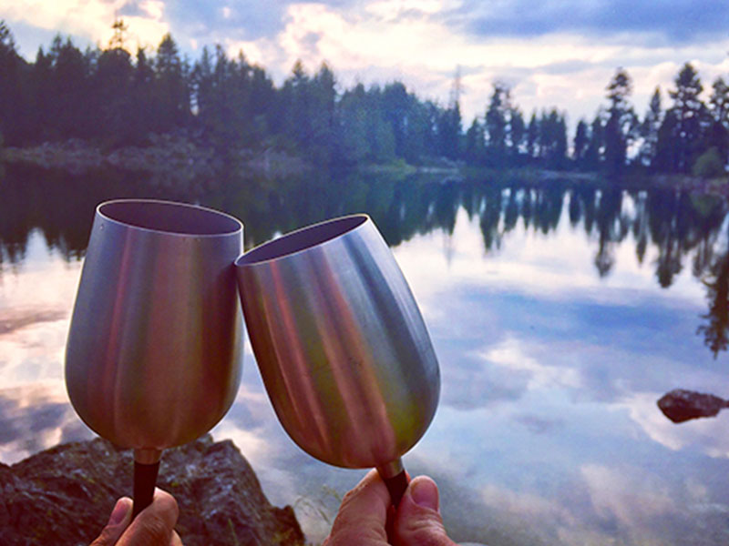 Two people making their first date more fun by having some wine by a lake.