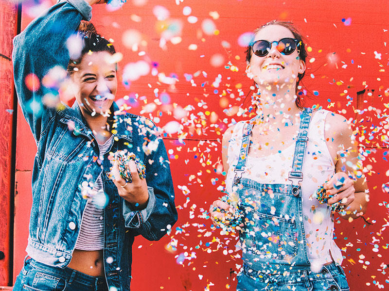 Two young girls throwing confetti being happy.