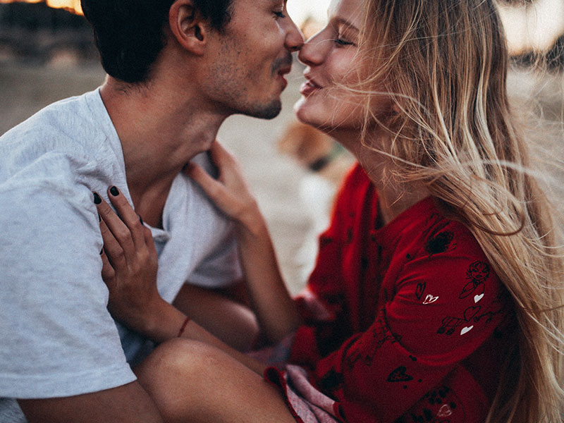 A man and women kissing on the beach who took these dating tips for 2018 to heart.