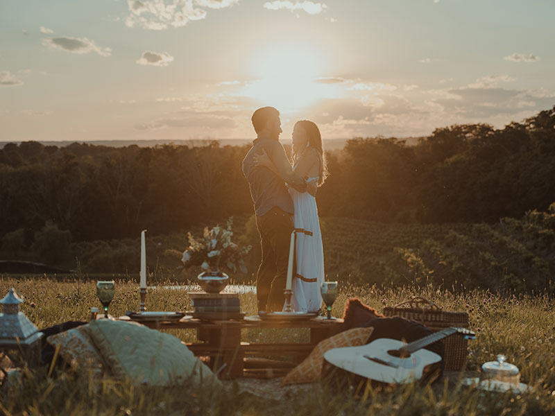 A man who used one of these ideas for romantic things to do standing on top of a hill at sunset with his happy girlfriend.