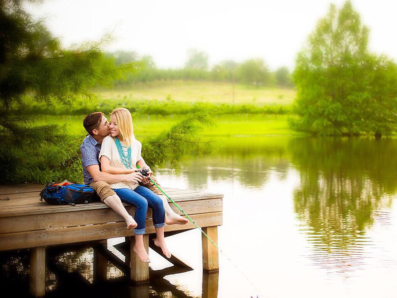 A man who's dating an extrovert as an introvert, fishing with his girlfriend on a dock and laughing.