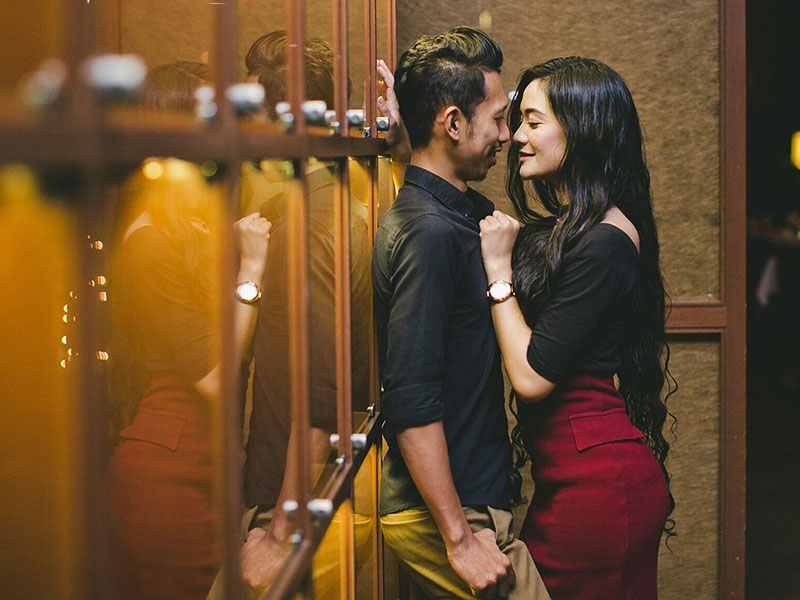 A couple in a secret relationship sneaking a kiss in an alley outside a restaurant.
