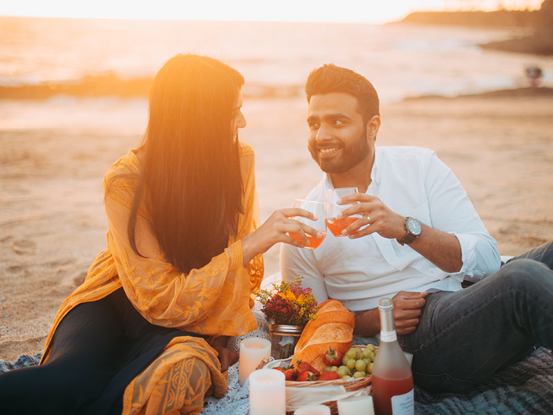 A couple who found what to talk about on a first date, cheersing on the beach.