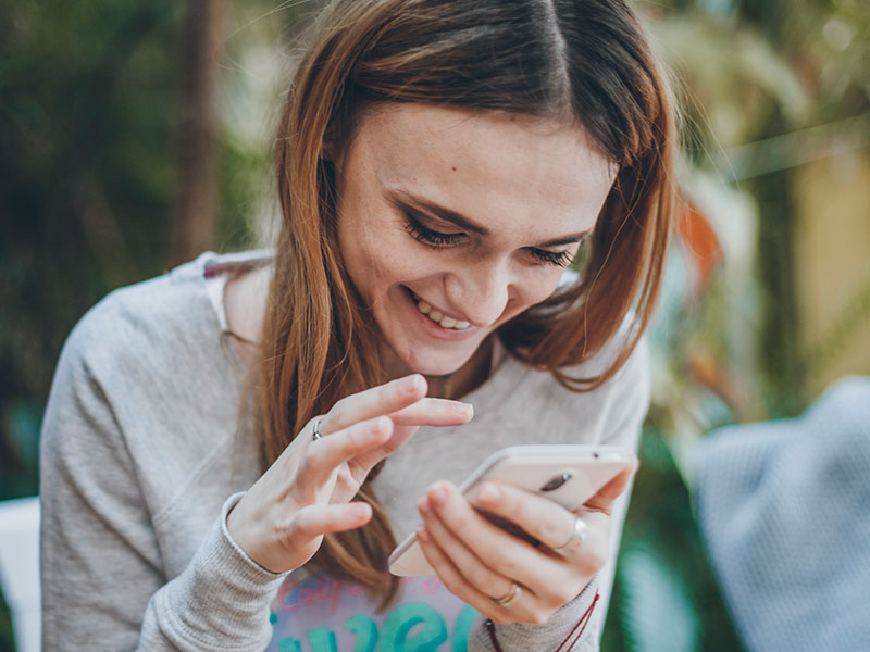 A woman sending flirty messages on her phone and laughing.