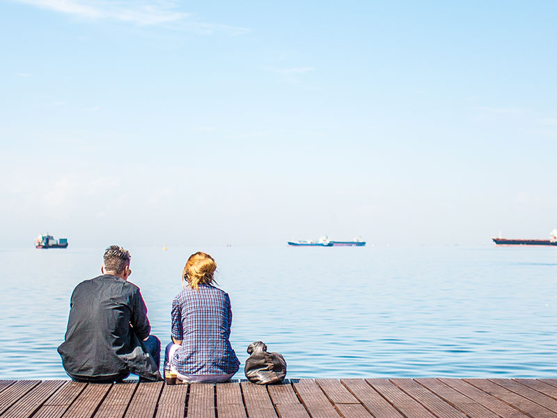 A woman who learned how to tell someone you're not interested talking to a guy she's seeing while they sit on a dock.