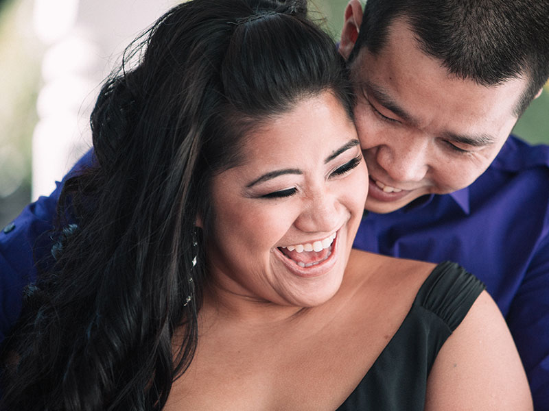 A couple that knows that love is sacrifice and compromise laughing with each other in the sun.