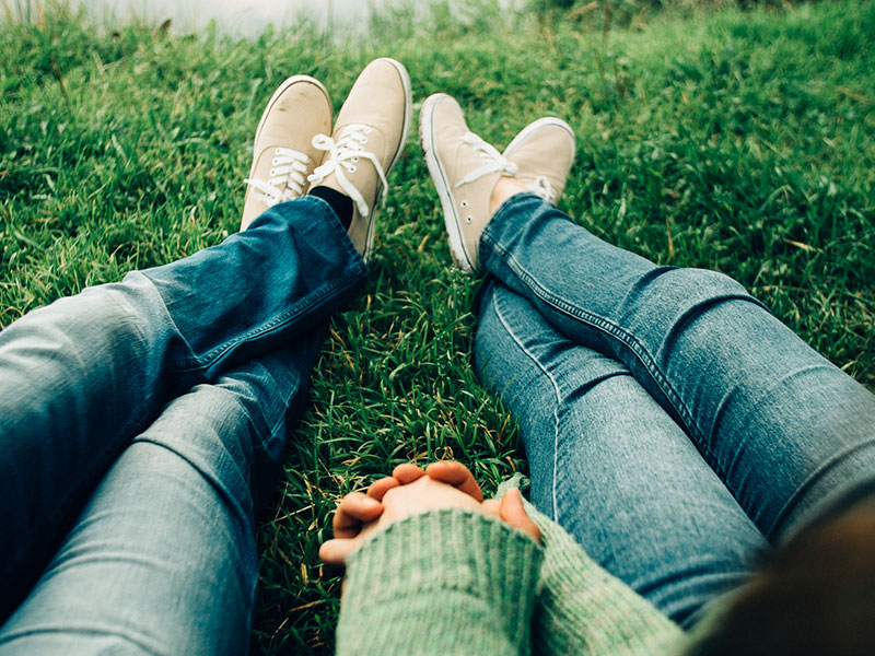 A couple holding hands in the grass while taking part in one of these bonding activities for couples.