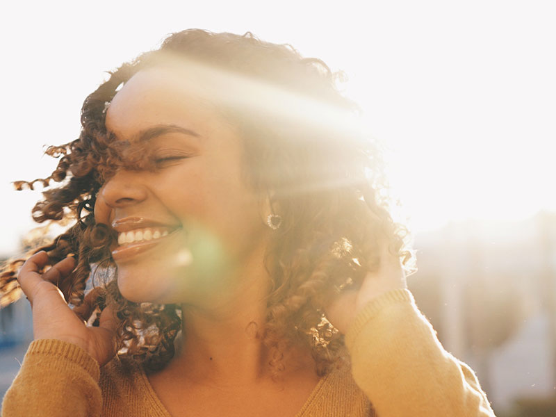 A woman smiling in the sun and enjoying her life after divorce.