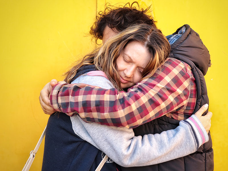A couple going through a marriage separation, hugging as they say goodbye for now.