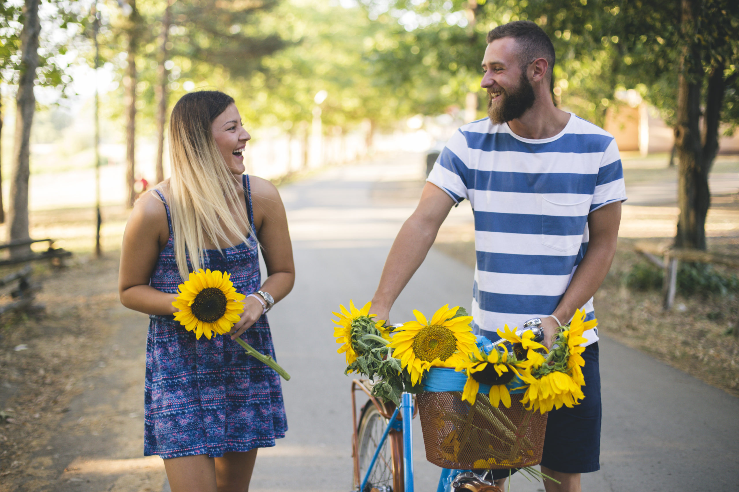 Happy young couple going for a bike ride on a sunny day in the park and looking out for the common signs of attraction in each other.