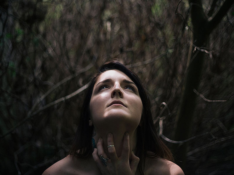 A woman who's experienced gaslighting, trying to make sense of her experience while standing in the woods.