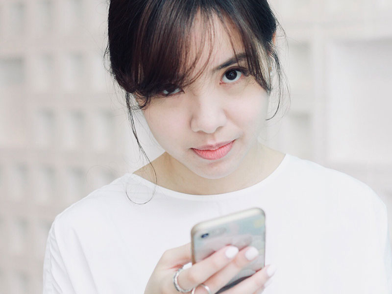 A girl making an annoyed face at her phone as she prepares to respond to breadcrumbing messages.
