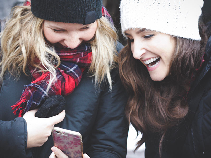 A girl who figured out what to say to someone who ghosted you, laughing with her friend as they text the guy back.
