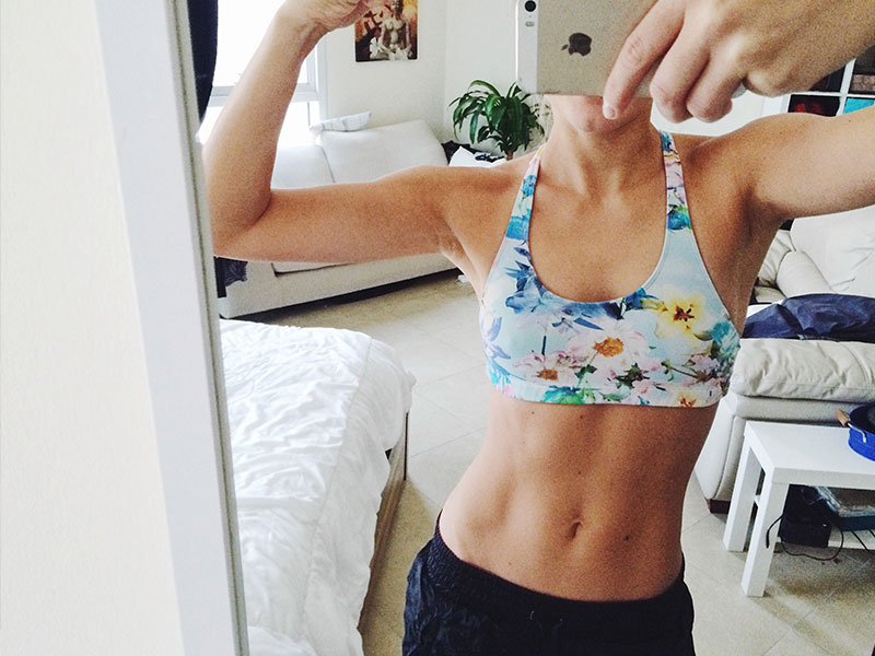 A woman posing in front of her bathroom mirror showing off her abs and doing one of these dating profile no nos.