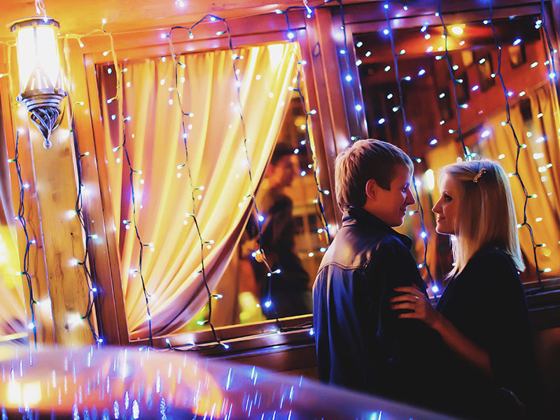 A couple sharing a holiday memory in the lights.