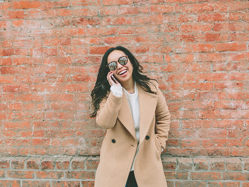 A woman showing proper phone etiquette and she laughs and talks on the phone with a guy she's newly dating.