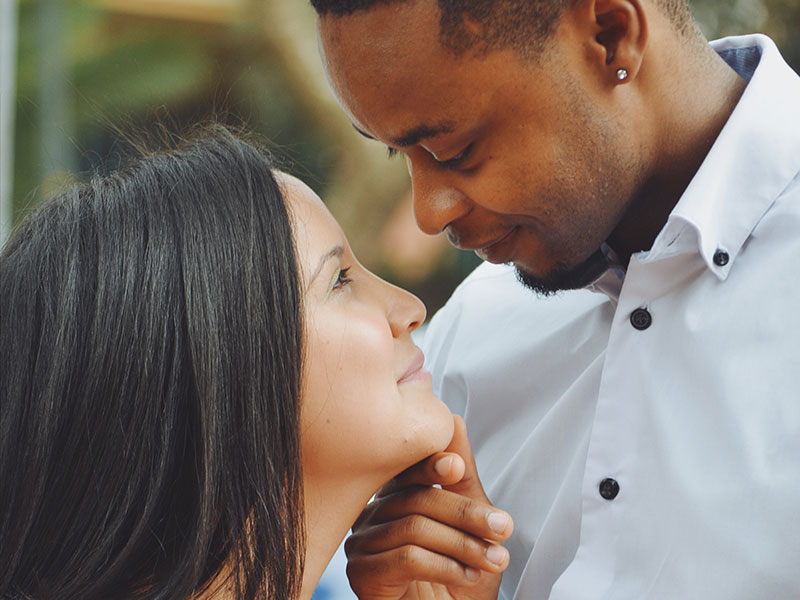 A couple who has mastered good communication in relationships smiling at each other outside at a party.