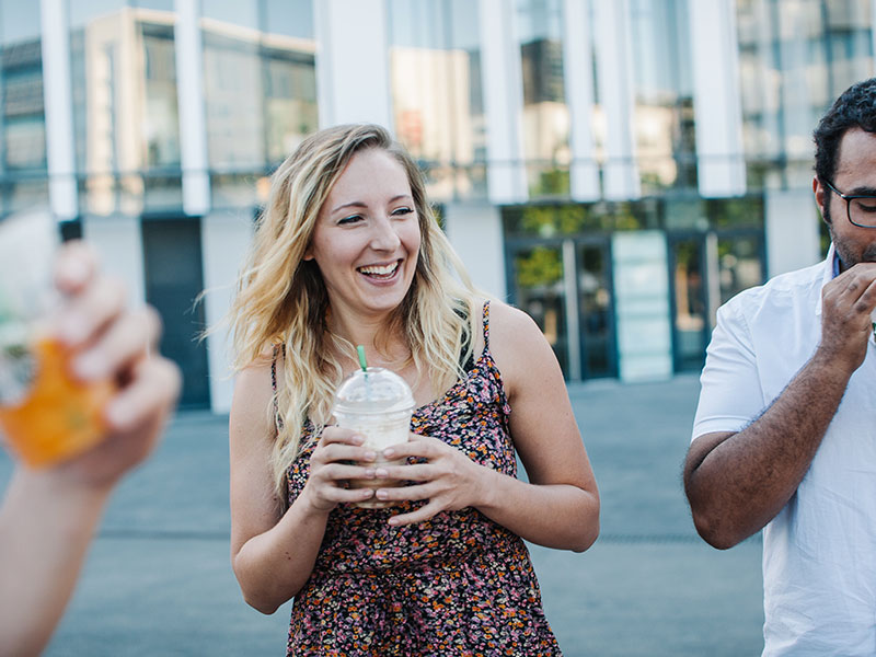 A women who is learning how to stop thinking about someone, out with her friends drinking coffee and laughing.