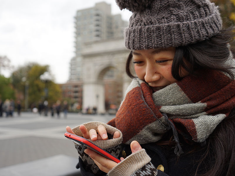 A woman who took these online dating tips, texting a guy on a dating app and laughing while wrapped in a scarf during cuffing season.