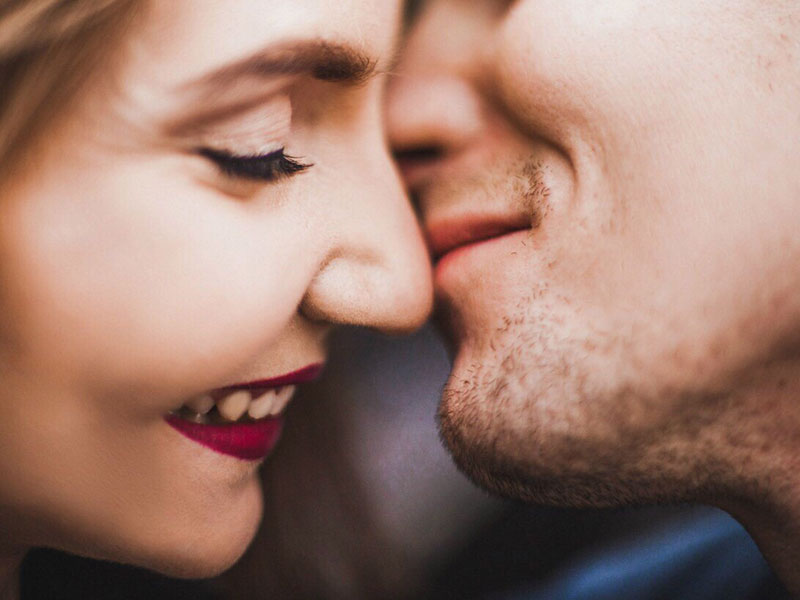 A couple who shared these reasons to love someone with each other smiling as they lean in for a kiss.