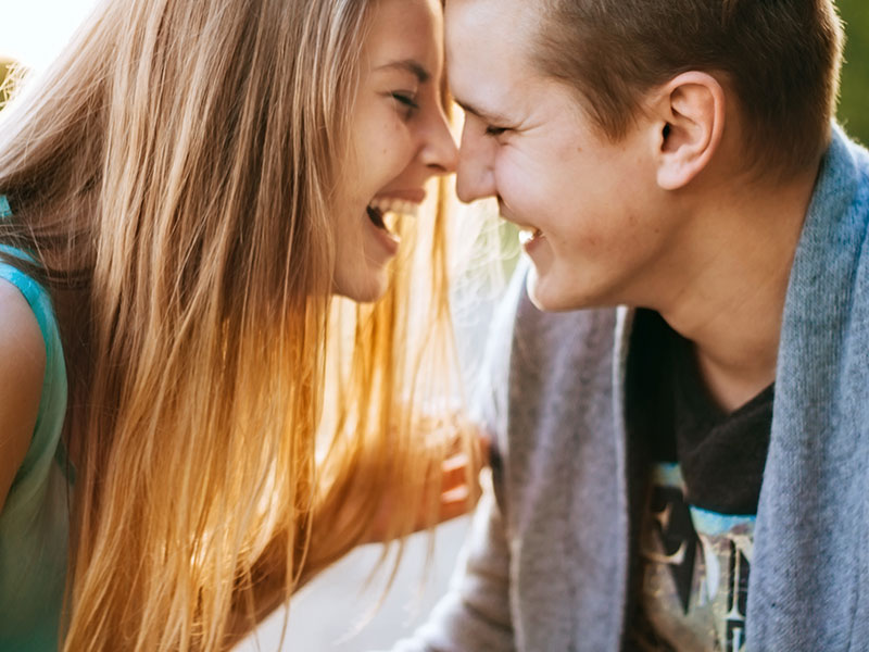 A woman who's a hopeless romantic laughing with her boyfriend and teasing him.