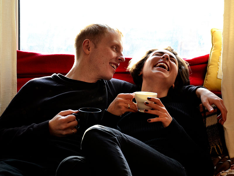 A woman who knows how to be a good girlfriend laughing with her boyfriend over coffee.