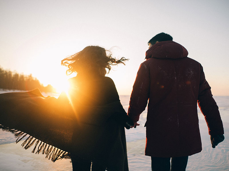 Two people running at sunset on the beach who believe in relationship anarchy and being free in their relationships.