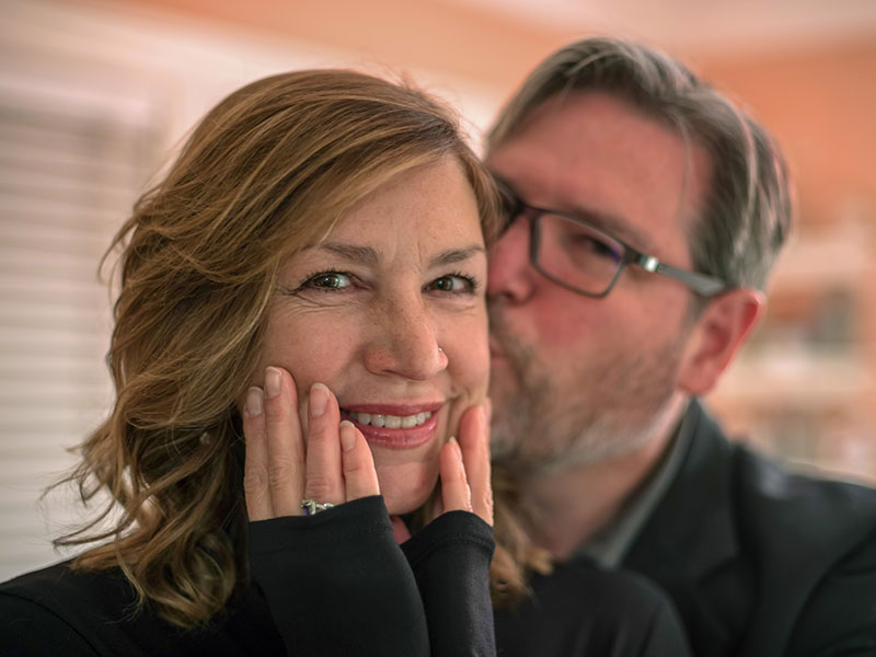 A couple senior dating, smiling together as the man kisses the woman's cheek.