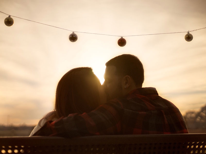 A man that learned how to love someone, kissing his significant other in front of the a sunset.