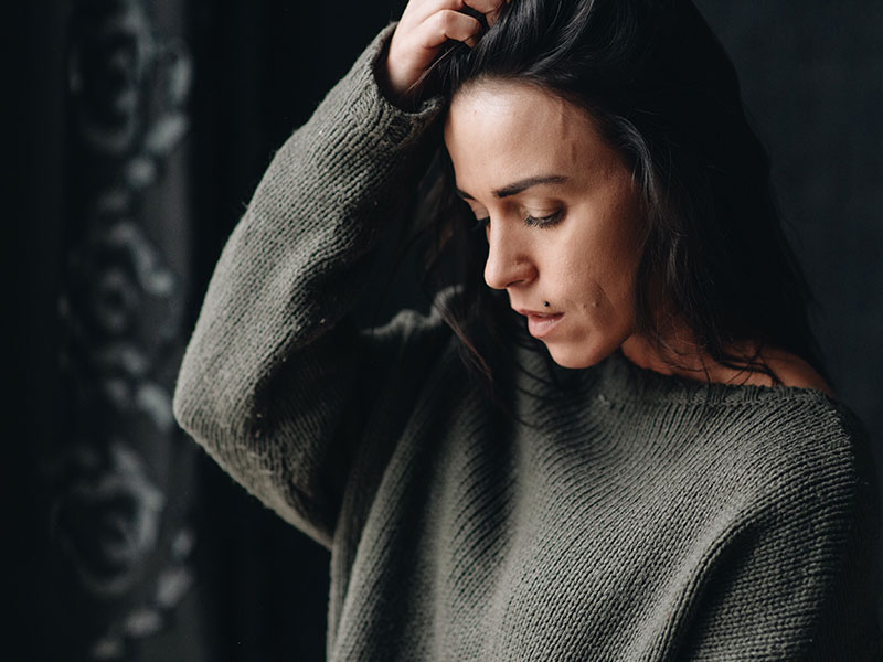 A woman who's worried her boyfriend doesn't love her, looking down and thinking.