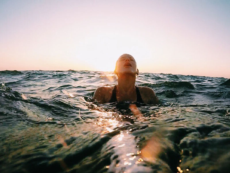A woman who is working on letting go of the past, coming up for a breath of air while swimming in the open ocean.