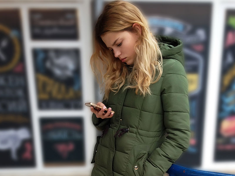 As girl who isn't over her ex, checking up on him on her phone and looking unhappy.