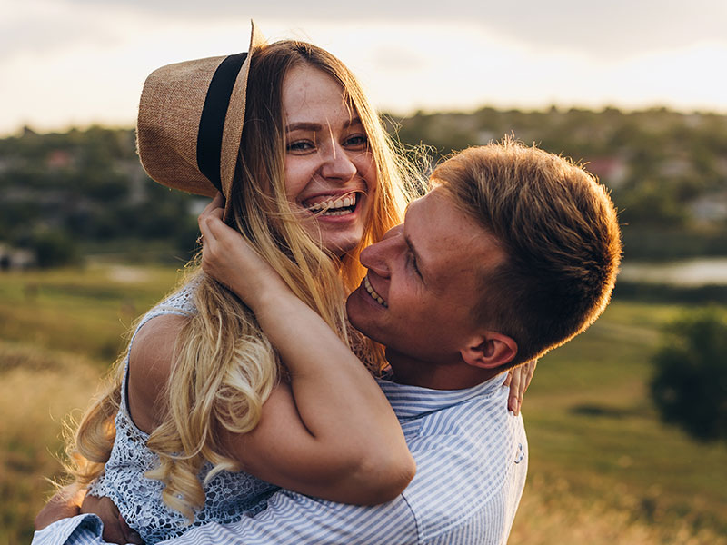 A couple laughing in a field together after listening to some of these traditional dating tips.